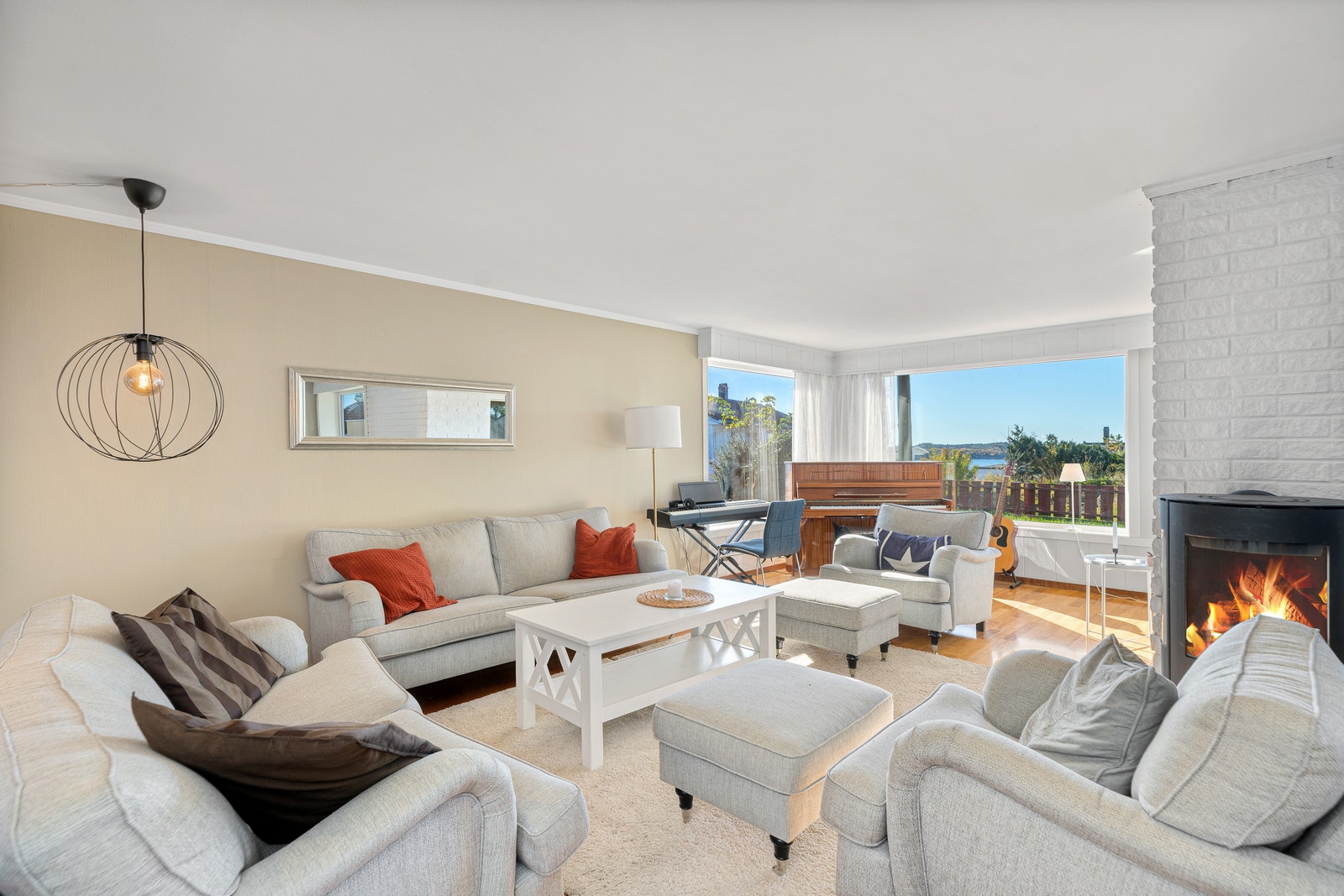 Lys stue med peis, store vinduer og god plass til sofa- og spisegruppe. Galleribilde