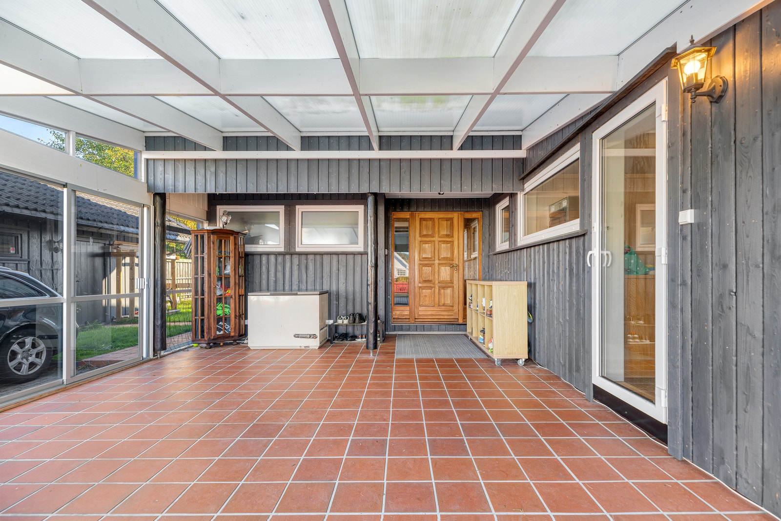 Overbygd uteplass med fliser utenfor inngangsparti og stue. Galleribilde