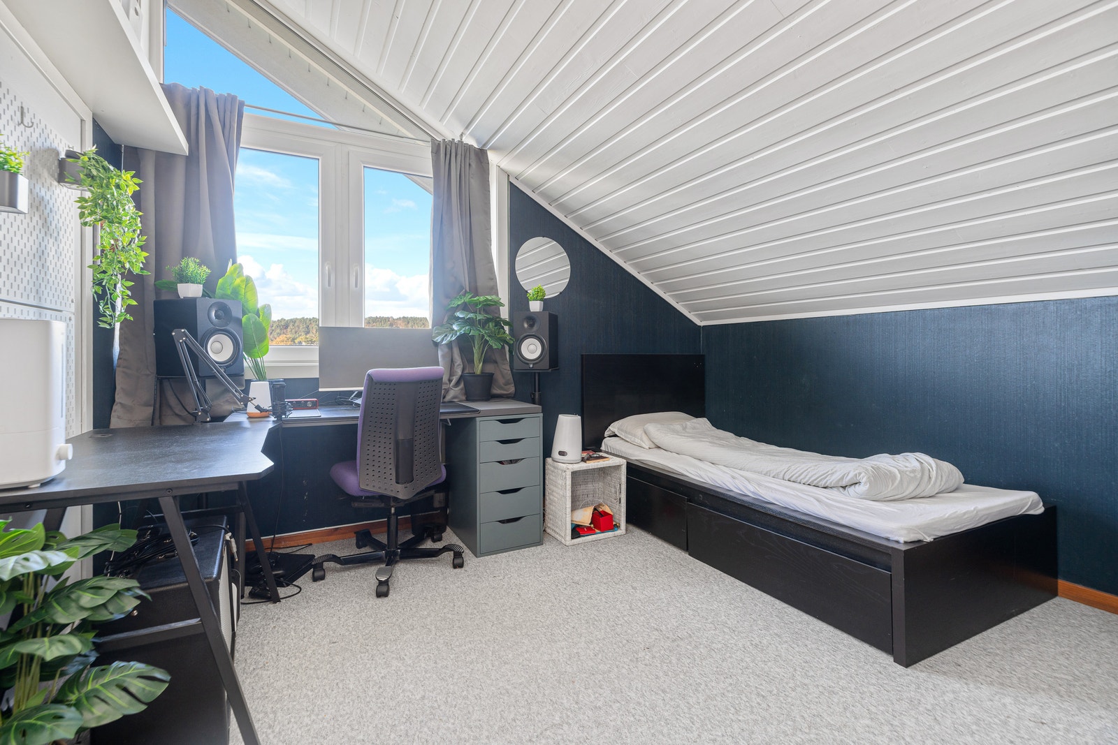 Soverom i overetasje med skråtak, seng og kontorplass. Galleribilde