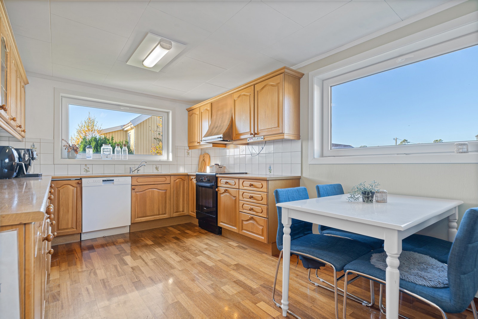 Kjøkken med trefronter, spiseplass og store vinduer. Galleribilde