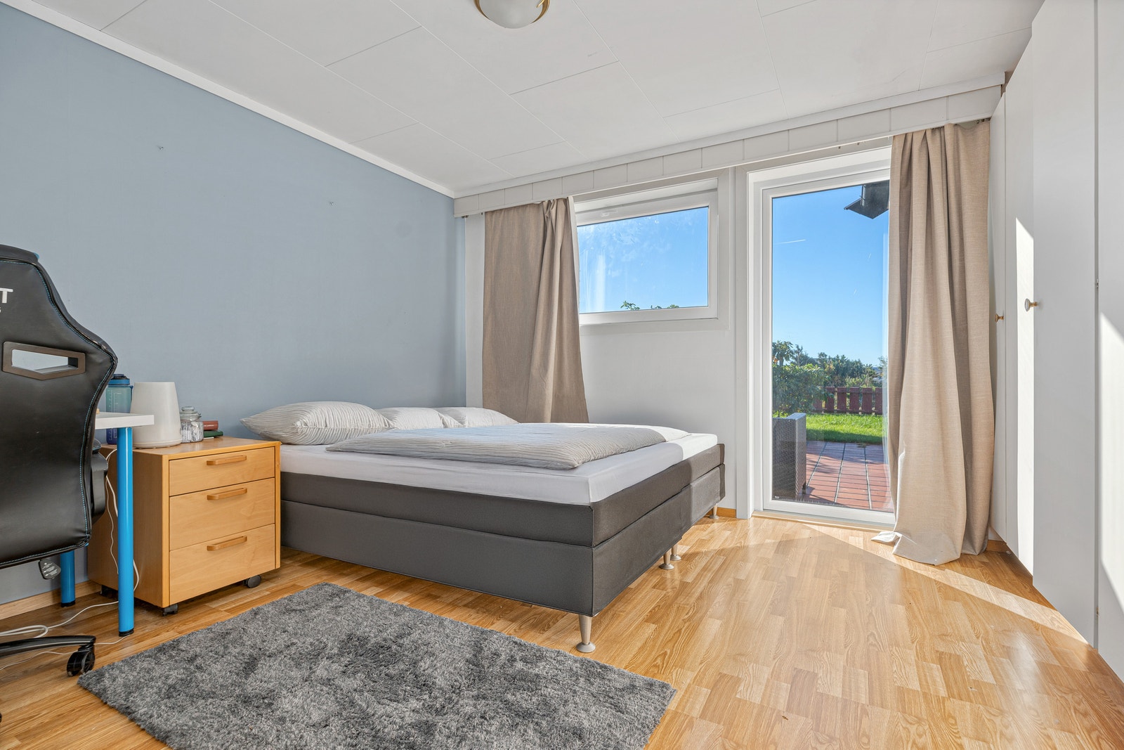 Soverom med dobbeltseng, nattbord, skrivepult og utgang til terrasse. Galleribilde