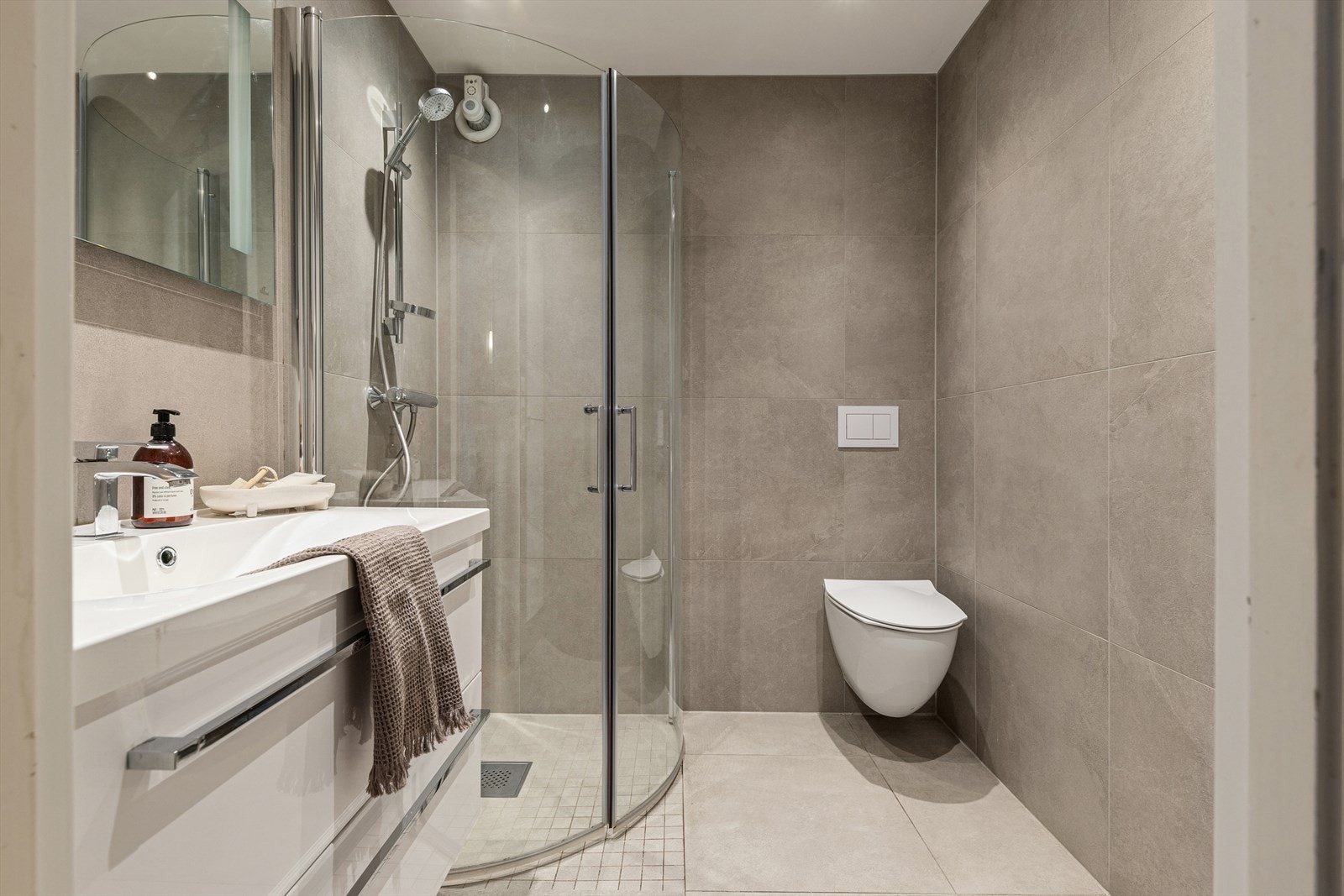 Flott baderom 1. etasje med innredning med nedfelt servant, nedsenkent dusjhjørne med glassvegger og vegghengt wc. Varmekabler i gulv. Galleribilde