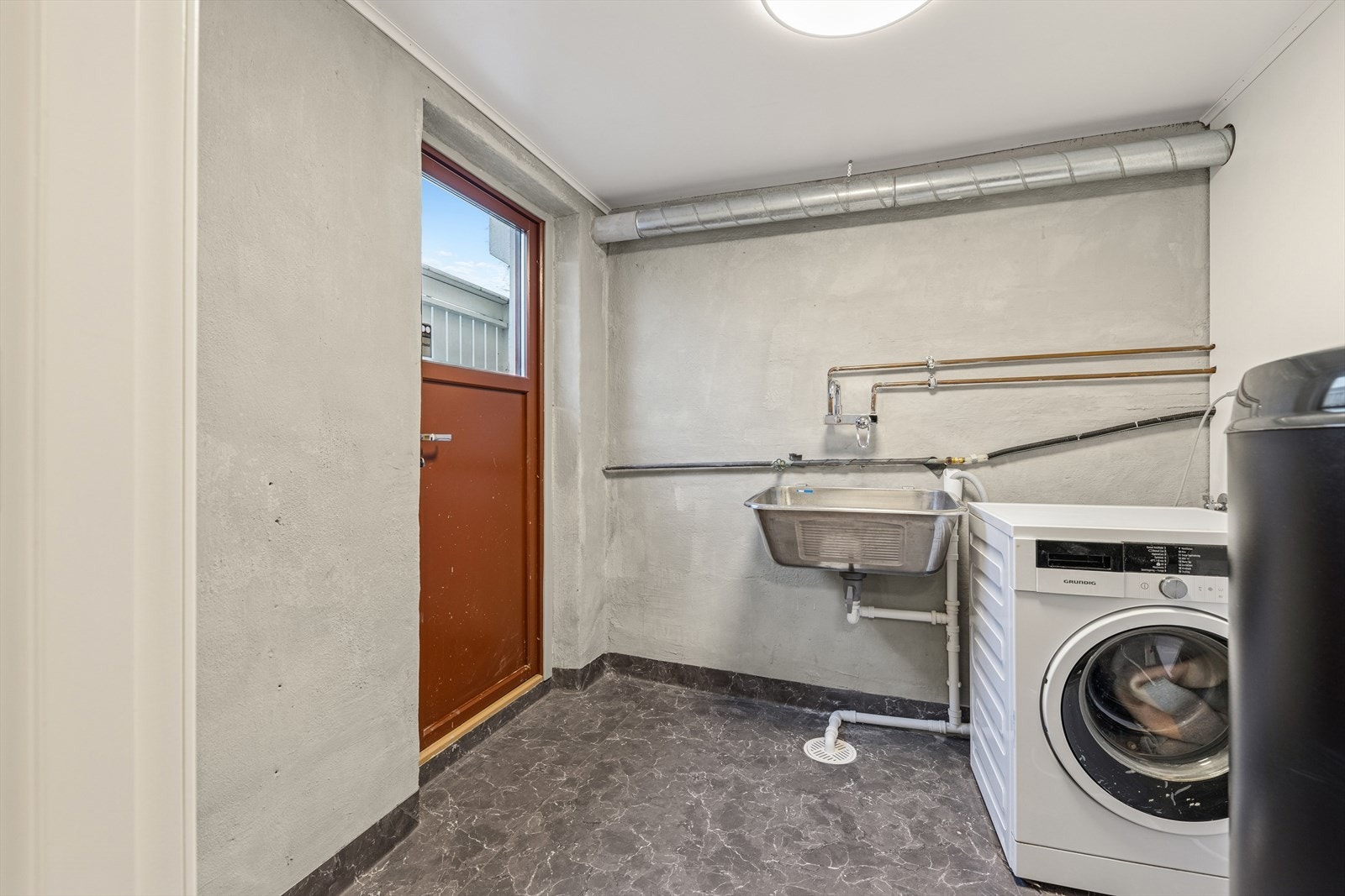 Vaskerom i kjeller med opplegg for vaskemaskin, vegghent utslagsvask og varmtvannsbereder. Galleribilde