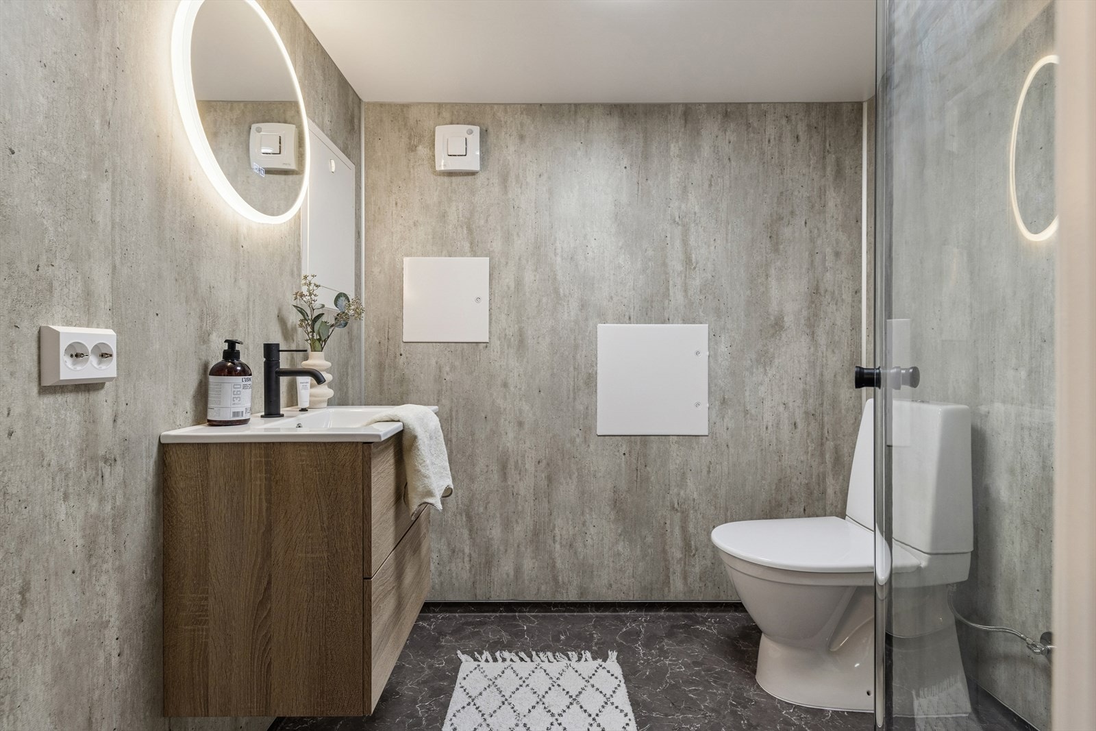 Stilrent baderom i kjeller med nedfelt servant, toalett og dusjhjørne med glassdører. Varmekabler i gulv. Galleribilde