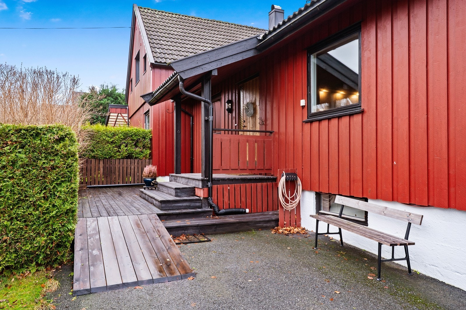 Overbygget inngangsparti med adkomst via en liten trapp og rampe. Galleribilde