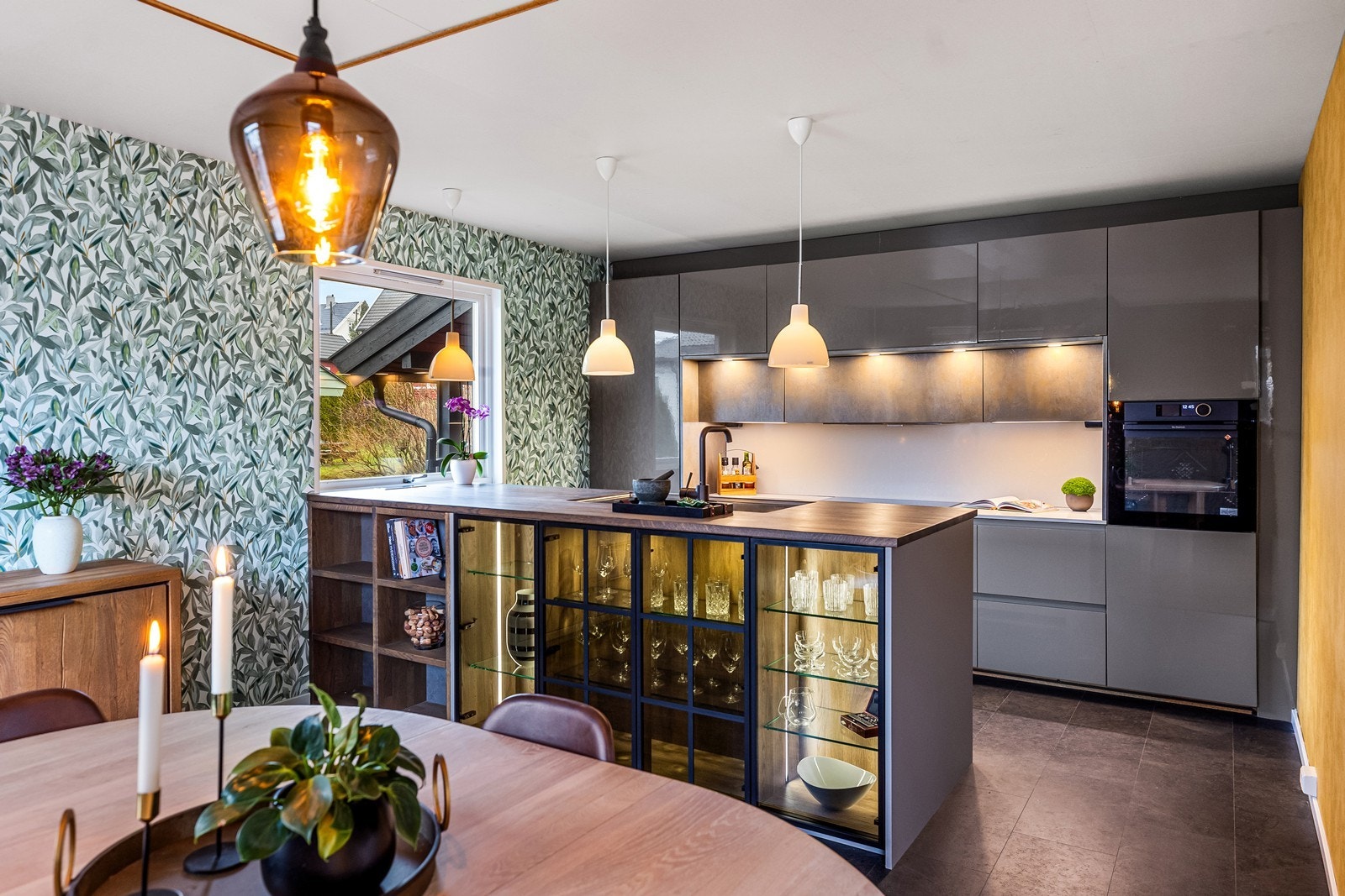 Kjøkkenøya fungerer som en sosial sone med barløsning og vitrineskap med belysning. Galleribilde