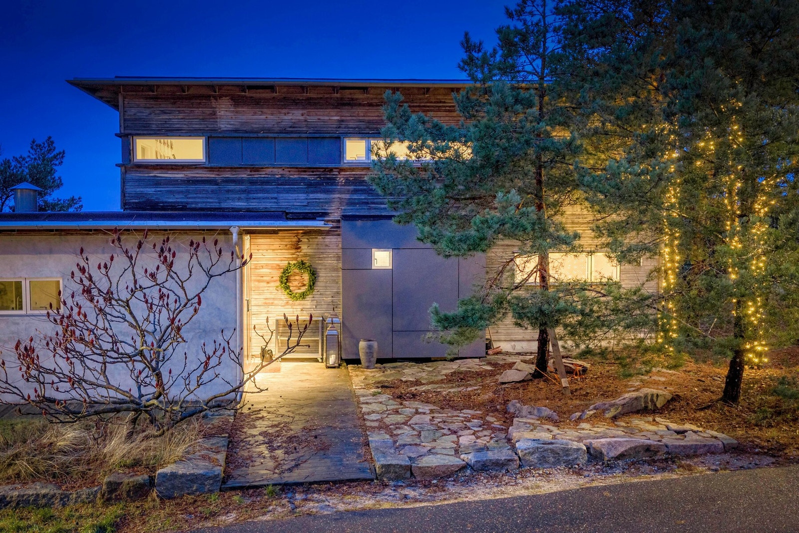 Mot gaten har boligen et diskret og rolig uttrykk - delvis dekket bak naturlig vegetasjon. Galleribilde