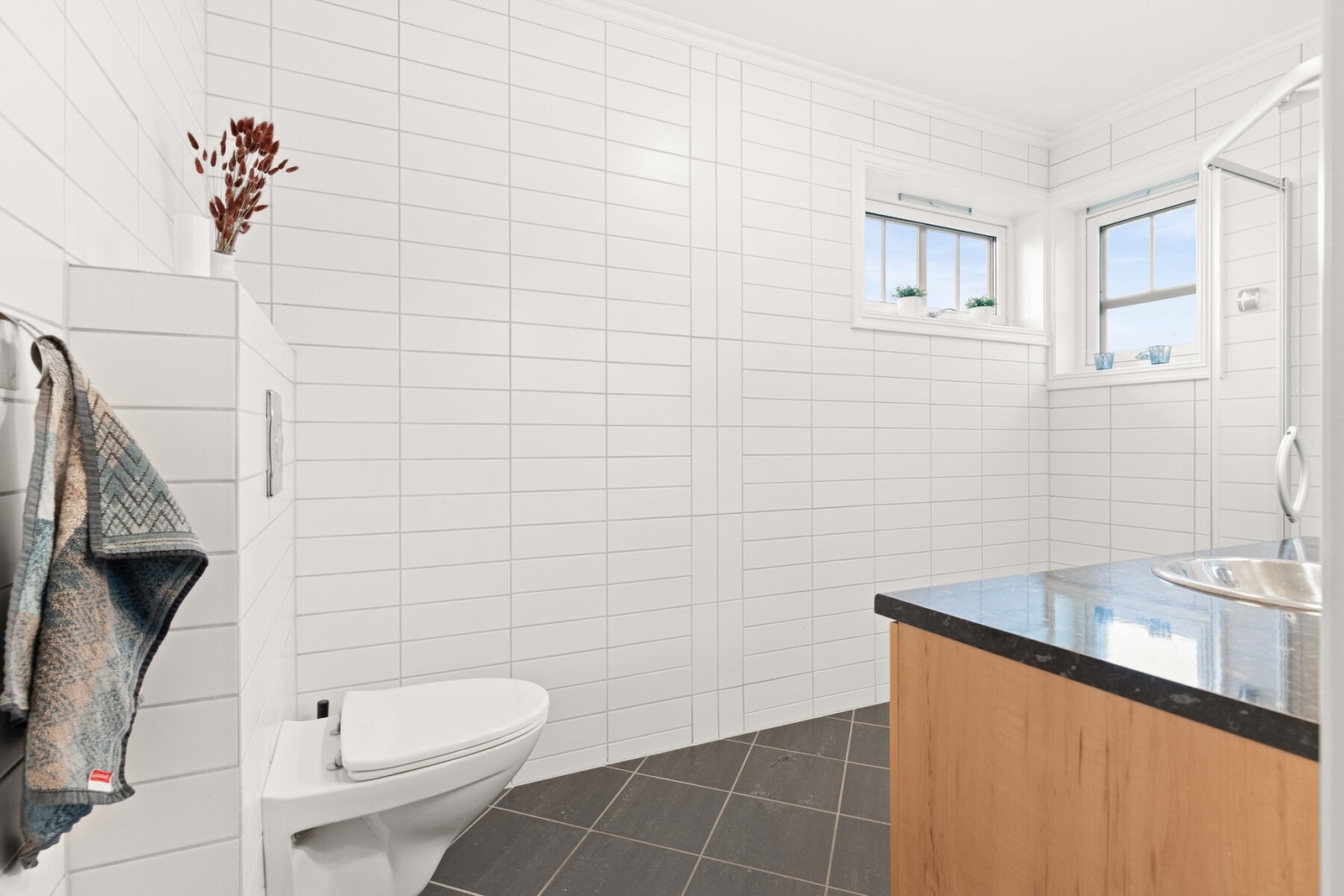 Innredning og garnityr på badet i 1. etasje fremstår med veggmontert WC, dusjplass med dusjvegger og servant med ettgreps blandebatteri i innredning. Galleribilde