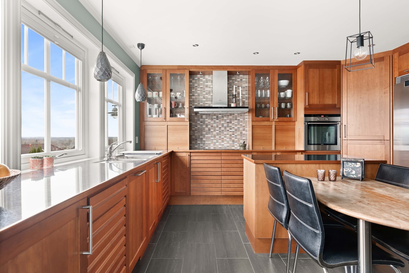 Over benken er det belysning og grå fliser, og over kokesonen har kjøkkenet en ventilator med avtrekk ut. Galleribilde