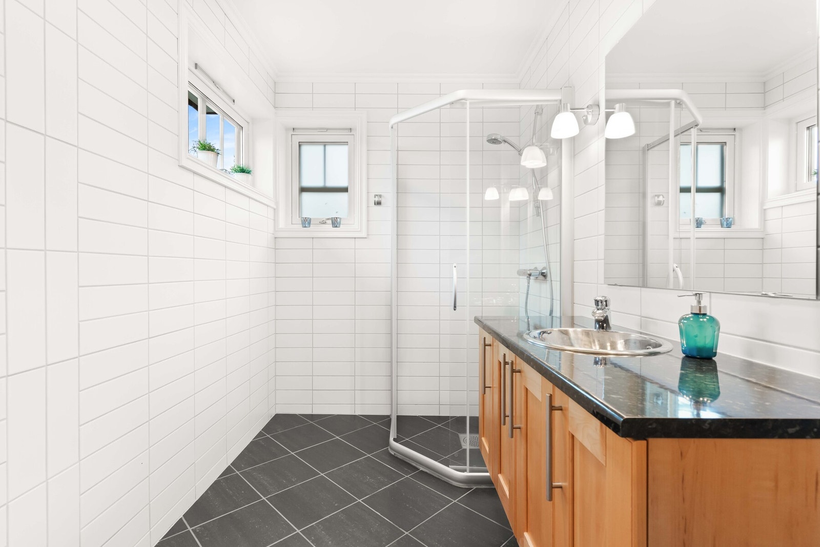 Badene er delikat innredet med mørke gulvfliser og hvite veggfliser. Varme er lagt i gulvet, og alle badene har vegghengt toalett. Galleribilde