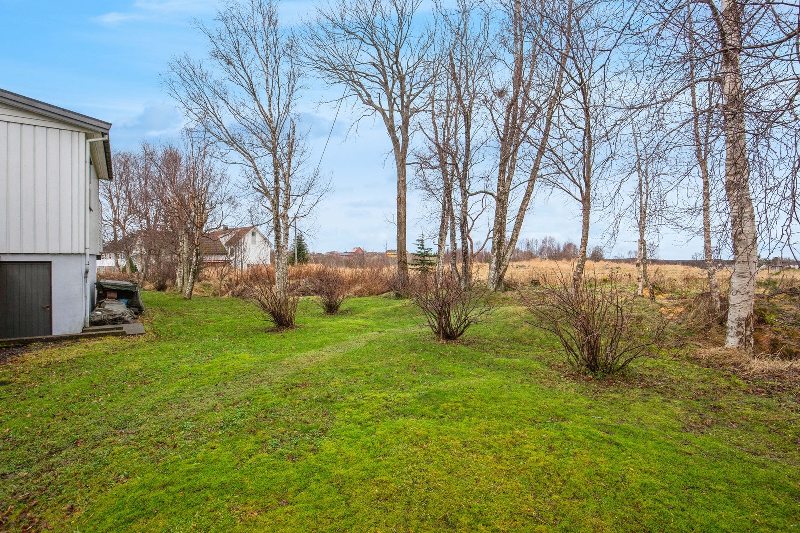 Tomten er pent opparbeidet med gruset innkjøring og plen rundt boligen Galleribilde