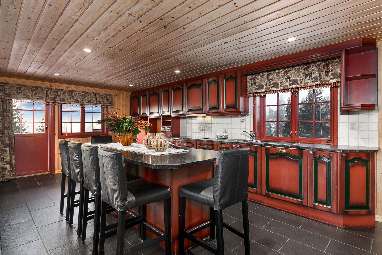 Innredningen består av røde profilerte fronter med mørke detaljer. Benkeplate i laminat med vaskekum i rustfritt stål. Galleribilde