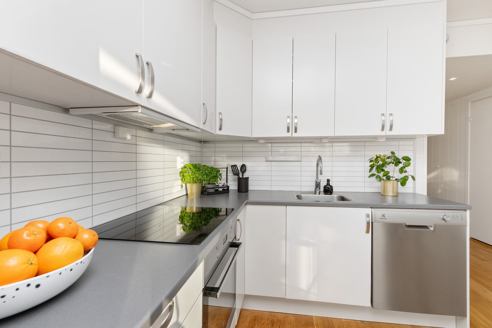 Laminat benkeplate md nedfelt oppvaskkum. Lys under overskap. Plater med flislook mellom benk og overskap. Galleribilde