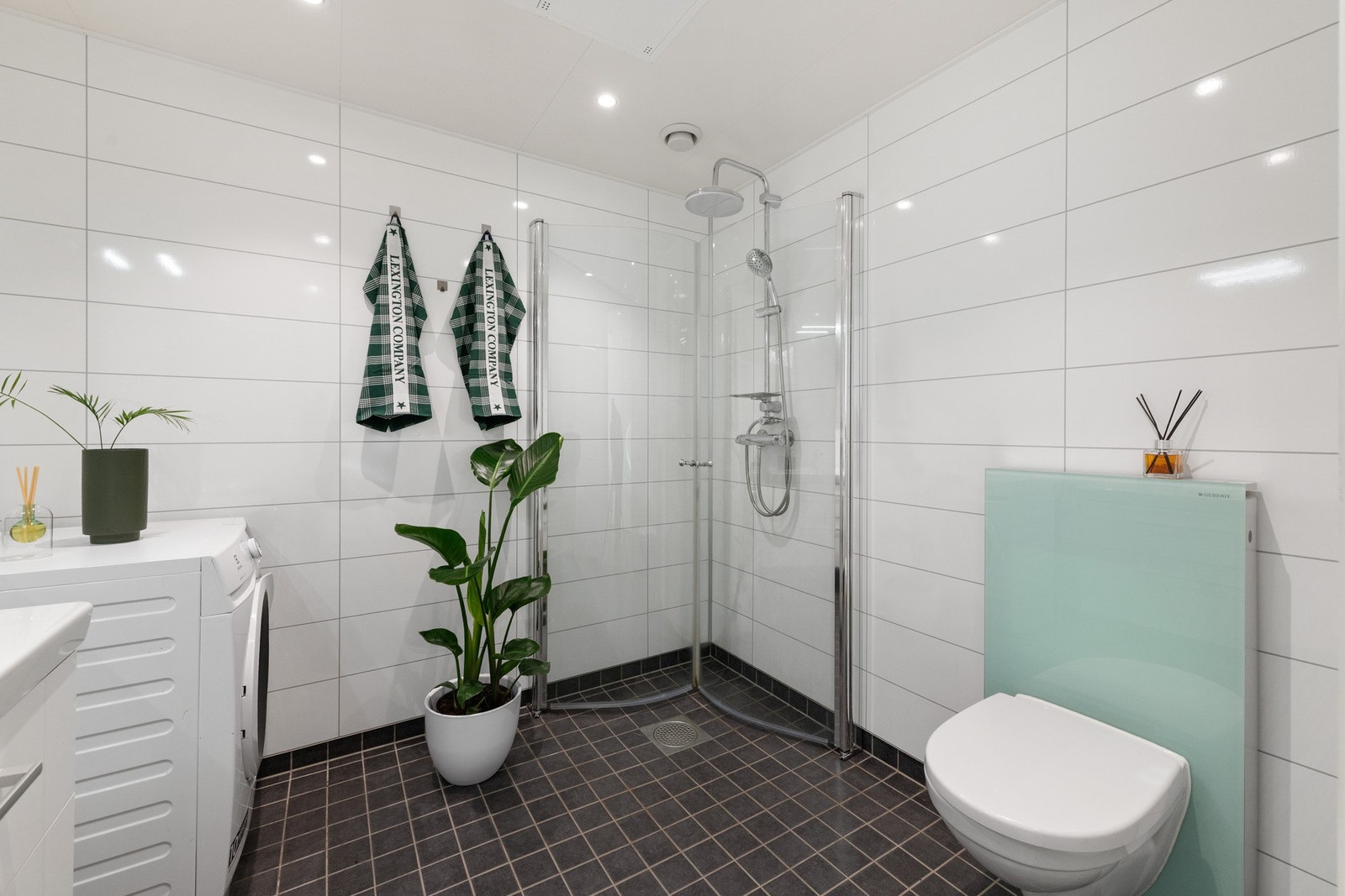 Vegghengt toalett og dusjhjørne med glassvegger. Opplegg for vaskemaskin. Galleribilde