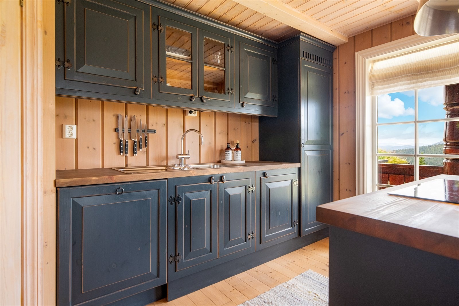 Gode arbeidsflater på heltre benkeplater med nedfelt oppvaskkum ved veggen og nedfelt induksjonstopp i kjøkkenøy. Videre er kjøkkenet utstyrt med integrerte hvitevarer. Galleribilde