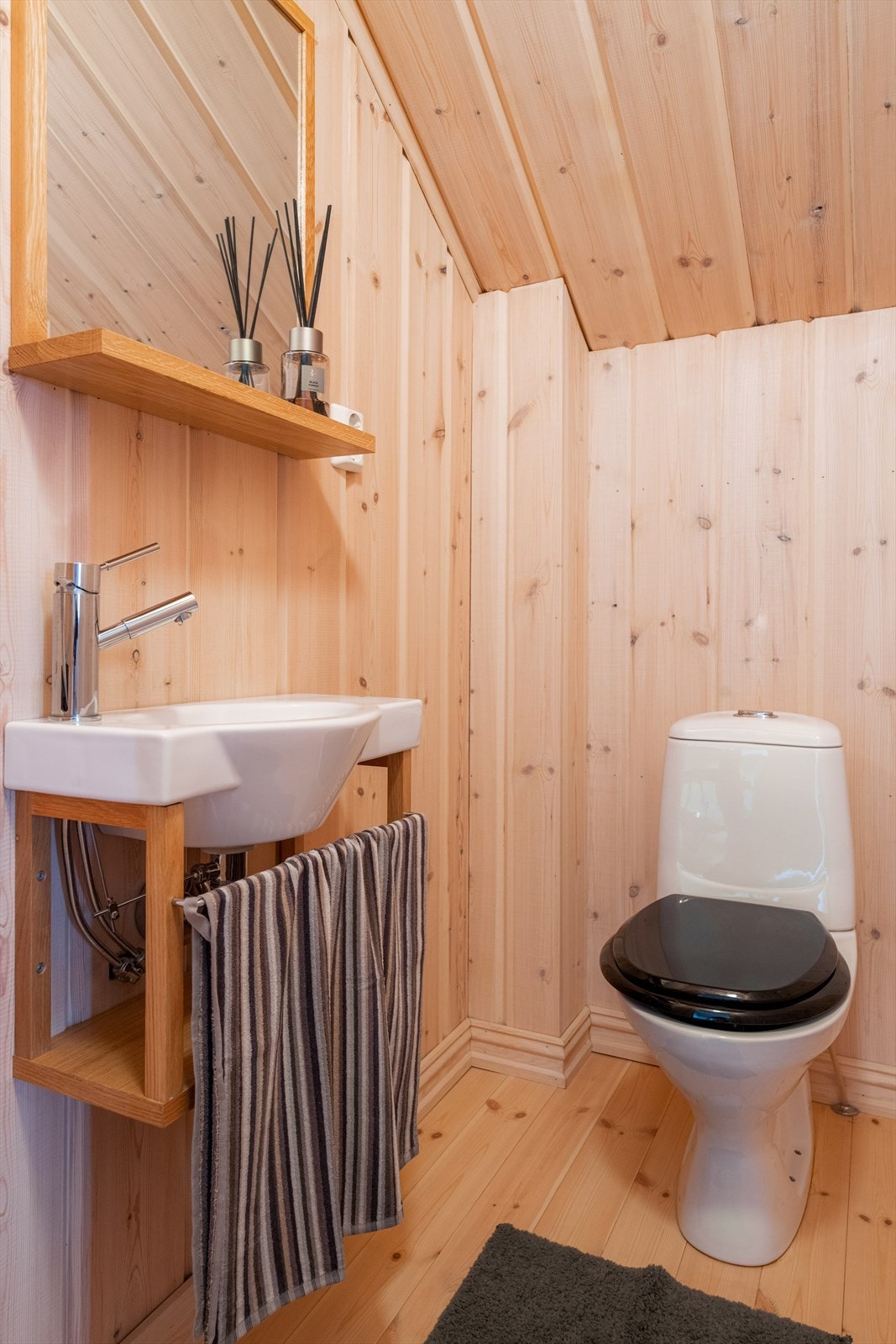Det er også et praktisk toalettrom i loftetasjen hvor det er furugulv og panelte overflater. Gulvmontert toalett og veggmontert servant med speil over. Galleribilde