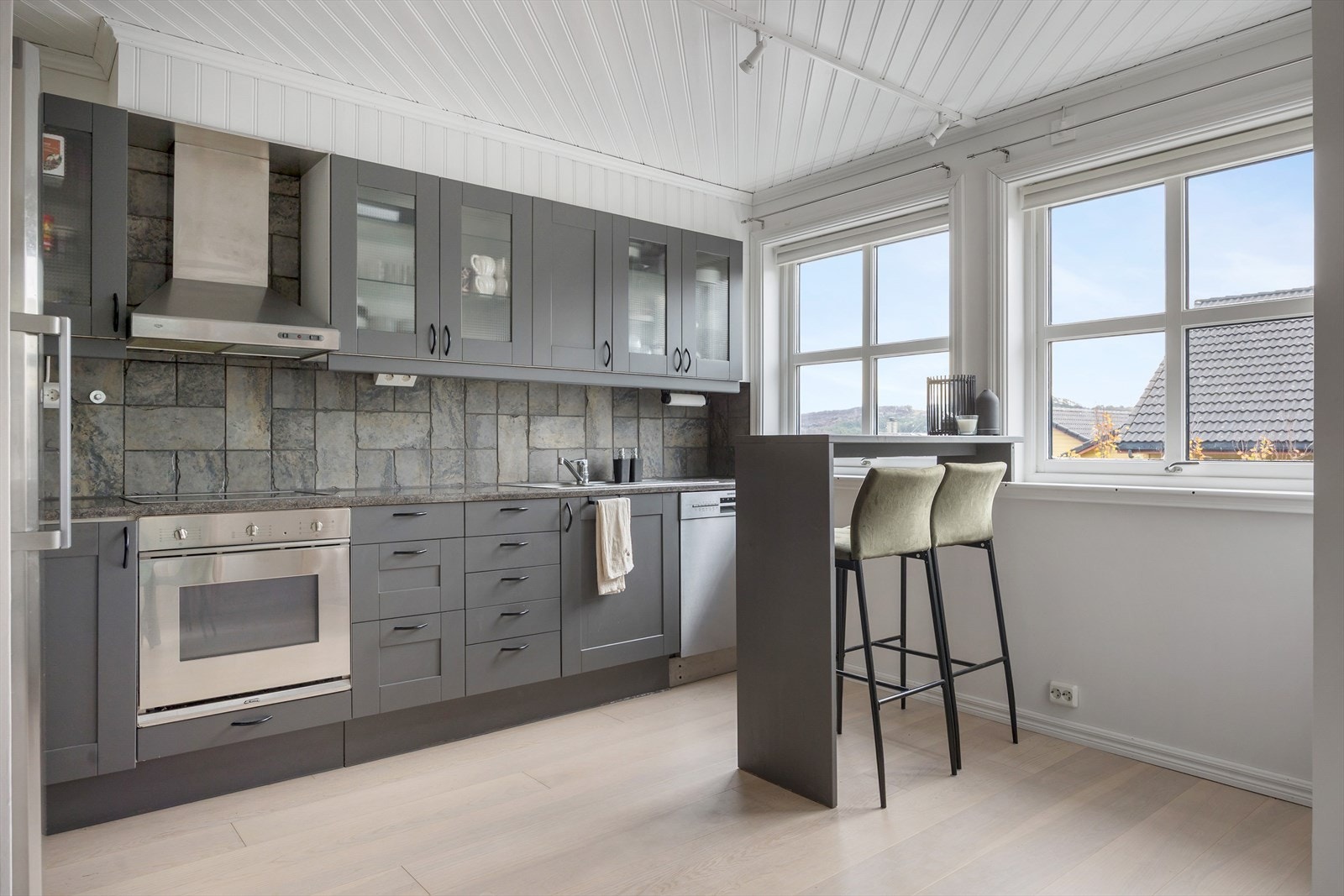 Kjøkkenet er del av en lys og luftig åpen løsning med stuen, som gir optimal utnyttelse av plassen. Kjøkkeninnredningen har malte fronter med speilprofil og benkeplate i laminat med nedfelte oppvaskkummer. Galleribilde