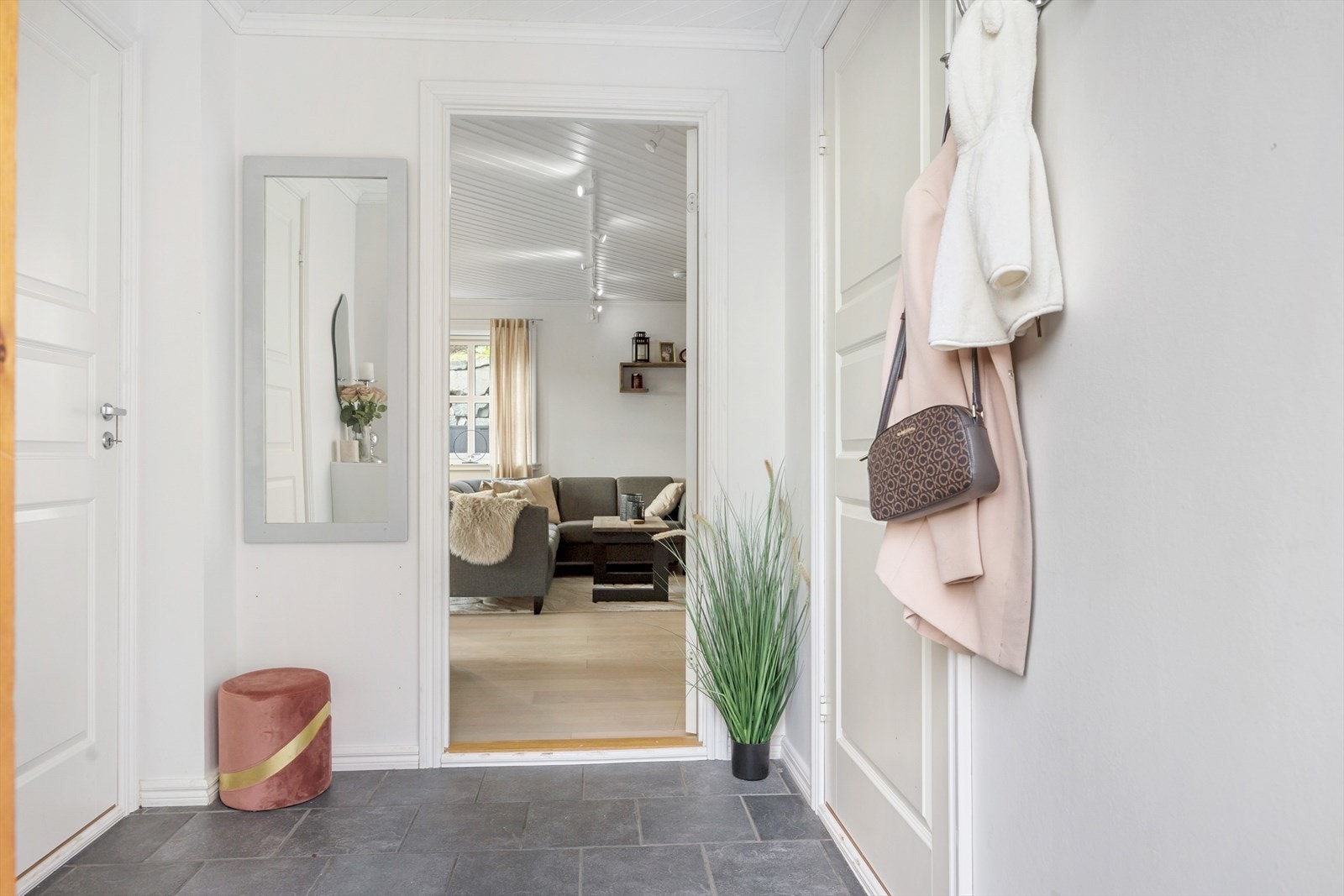 Når du kommer inn, blir du møtt av en innbydende gang med flislagt gulv og varme under føttene. Rett til høyre finner du et praktisk rom som kombinerer bod, vaskerom og teknisk rom. Her er det god plass til både oppbevaring og klesvask. Galleribilde