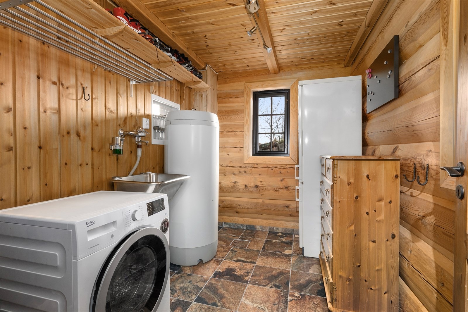 Inntil inngangspartiet er det eget vaskerom med flislagt gulv og varmekabler. Vaskerommet er praktisk innredet med skyllekum, opplegg for vaskemaskin og ekstra hylleplass. Her er det også muligheter for å ha et ekstra kjøl/fryseskap. Galleribilde