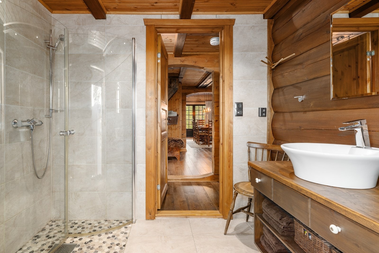 Hytta har et romslig bad med flislagt gulv og varmekabler. Her er stilen på hytta videreført, med både laft og flis på veggoverflatene. Badet har innredning med skuffer og hyller, samt heltre benkeplate med toppmontert servant. Galleribilde