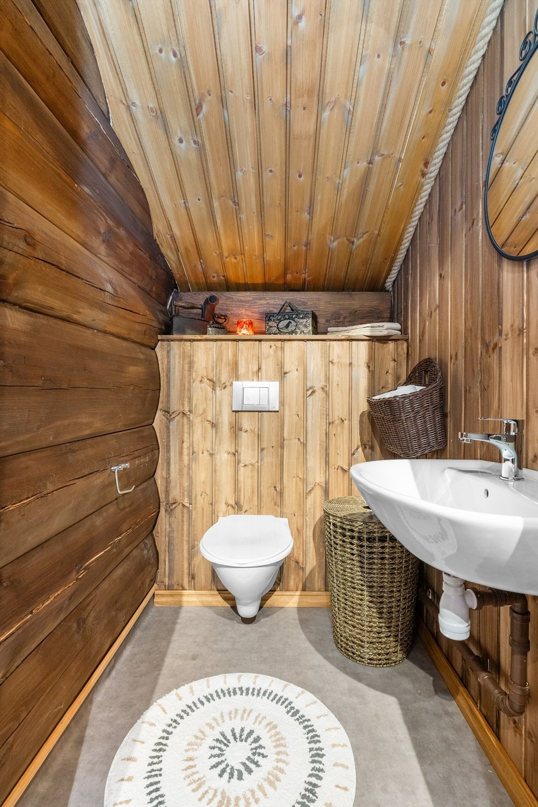 Toalettrommet i 2. etasje er etablert i 2025, med belegg på gulv og tømmer/panel på veggoverflatene. Rommet har en enkel servant og veggmontert toalett. Galleribilde