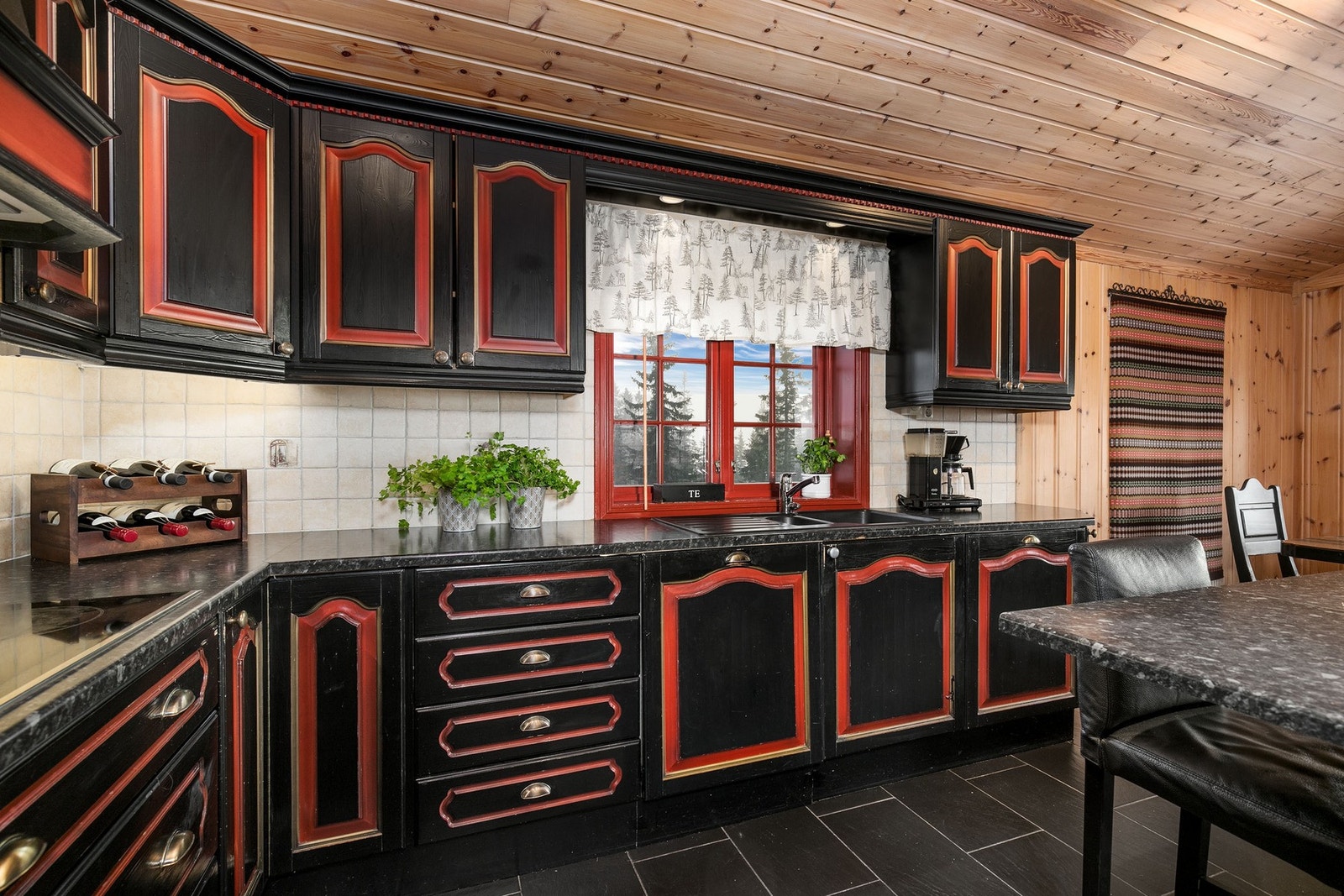 Innredningen består av mørke profilerte fronter med røde detaljer. Benkeplate i laminat med vaskekum i plastkompositt Galleribilde