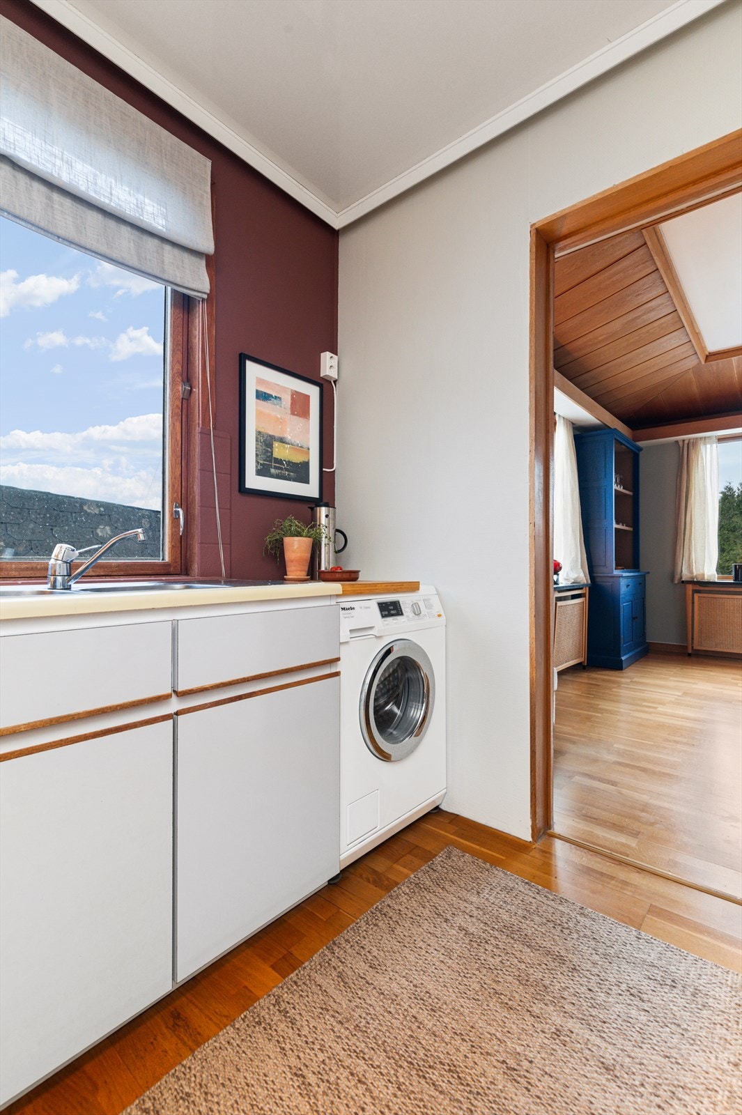 Kjøkken har kjøkkeninnredning med malte glatte skapfronter og benkeplater av laminat med nedfelt vask | innredningen har kjøkkenventilator med mekanisk avtrekk og utsparing for komfyr, oppvaskmaskin og vaskemaskin Galleribilde