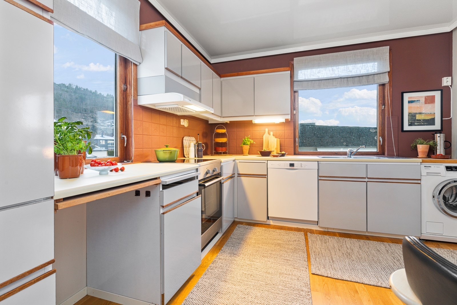 Kjøkken har kjøkkeninnredning med malte glatte skapfronter og benkeplater av laminat med nedfelt vask | innredningen har kjøkkenventilator med mekanisk avtrekk og utsparing for komfyr, oppvaskmaskin og vaskemaskin Galleribilde