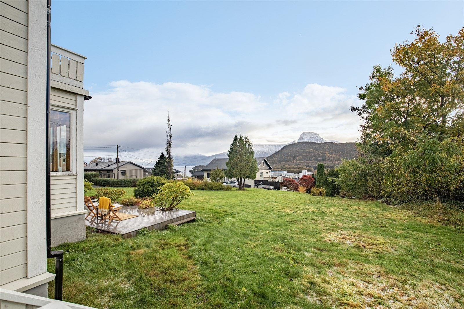 Fasade/hage | sydøstvendt tomt på 973,7 m² er pent opparbeidet med treterrasse, blomsterbed, plen og beplanting Galleribilde