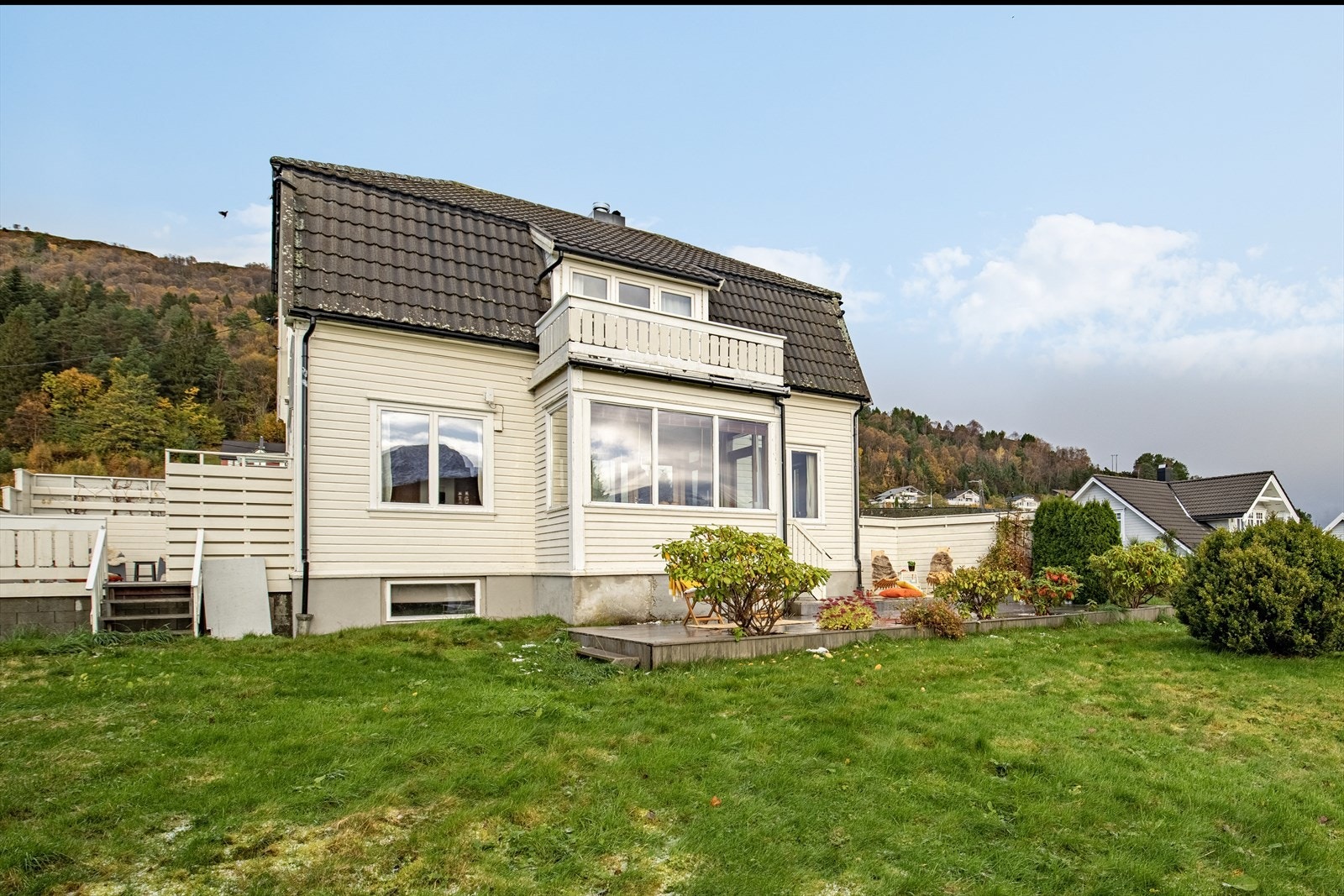 Boligen ligger på sydøstvendt tomt som er pent opparbeidet med treterrasse, blomsterbed, plen og beplantning Galleribilde