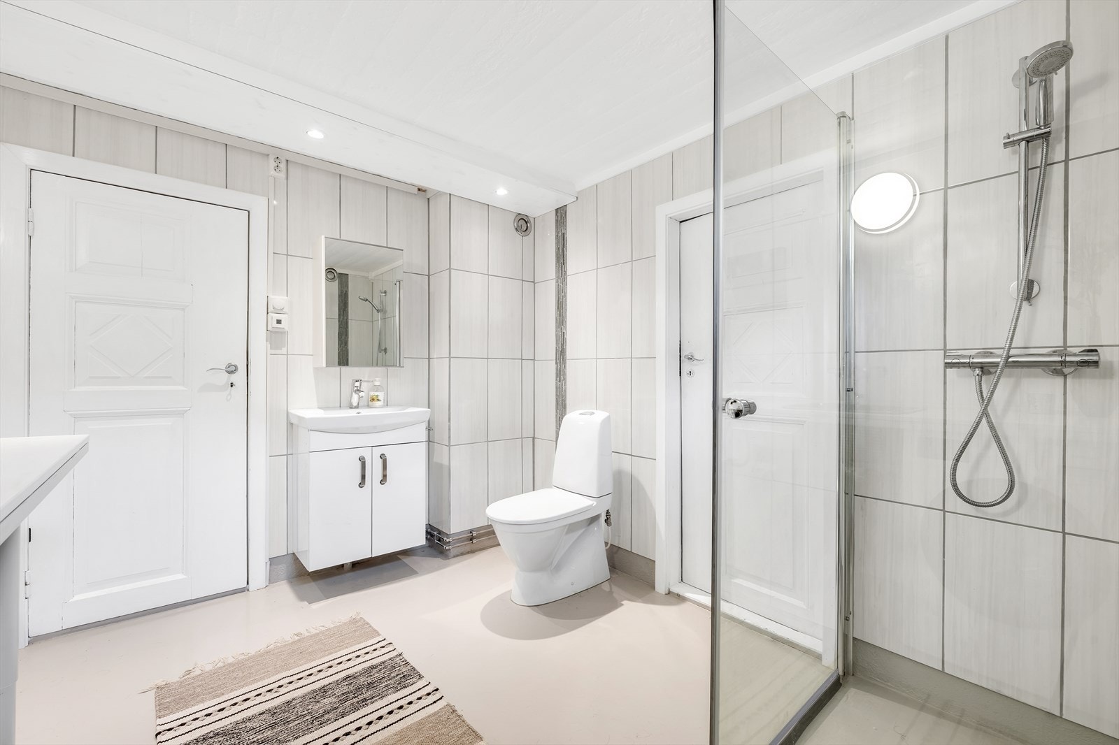 Kjellerbad/vaskerom med dusj, servantskap og varme i gulv. Et rom som dekker familiens behov. Galleribilde