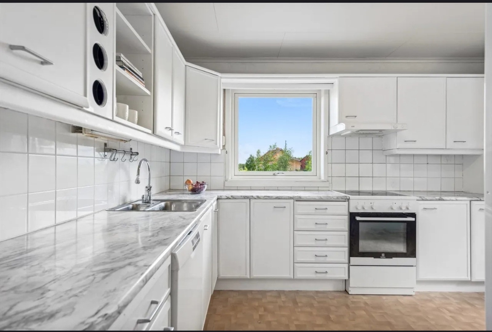 Kjøkkenet har profilerte fronter som ble malt i 2024, og fliser over benkeplaten. Galleribilde