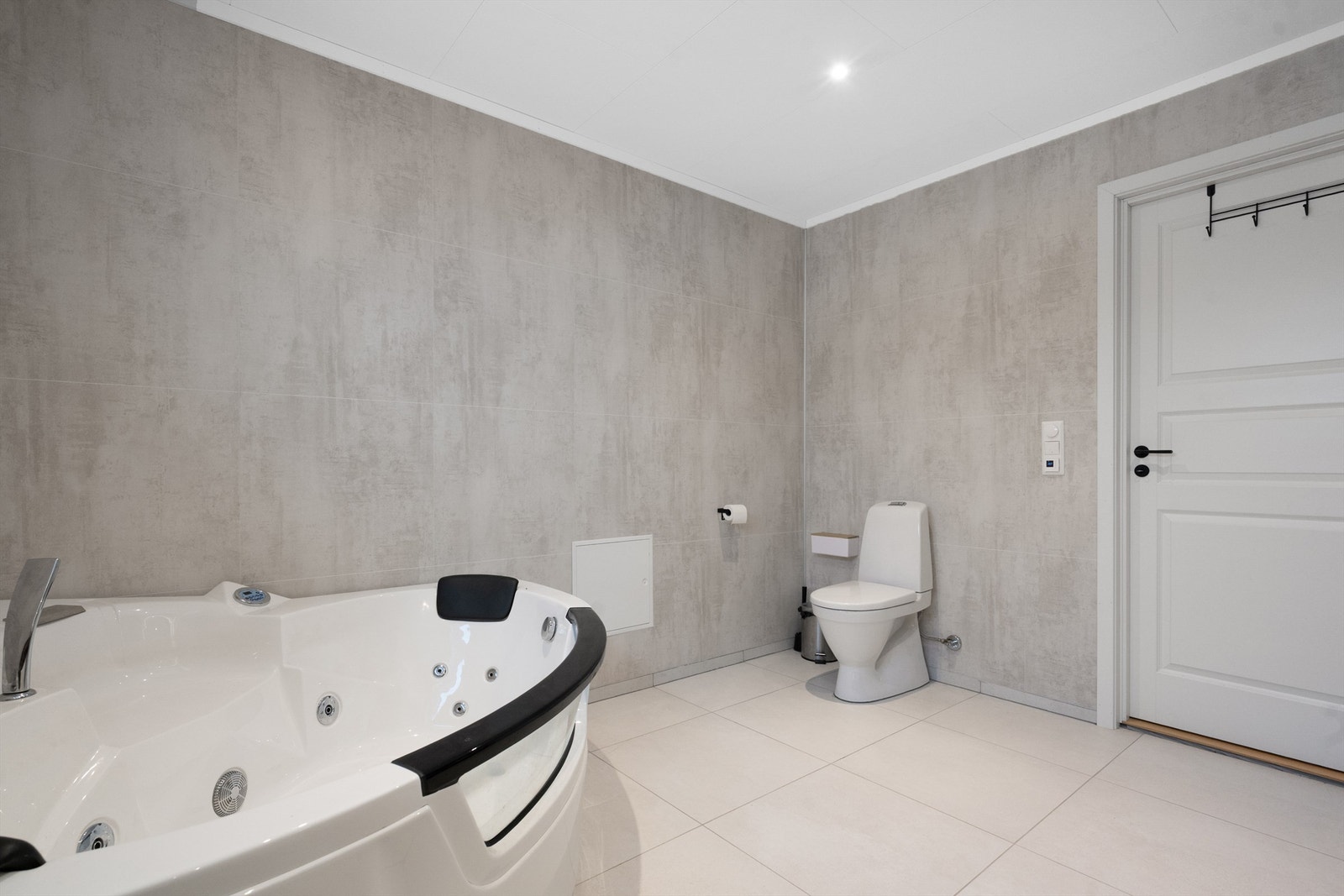 Store fliser på gulv og baderomsplater på veggene gir et helhetlig inntrykk. Galleribilde