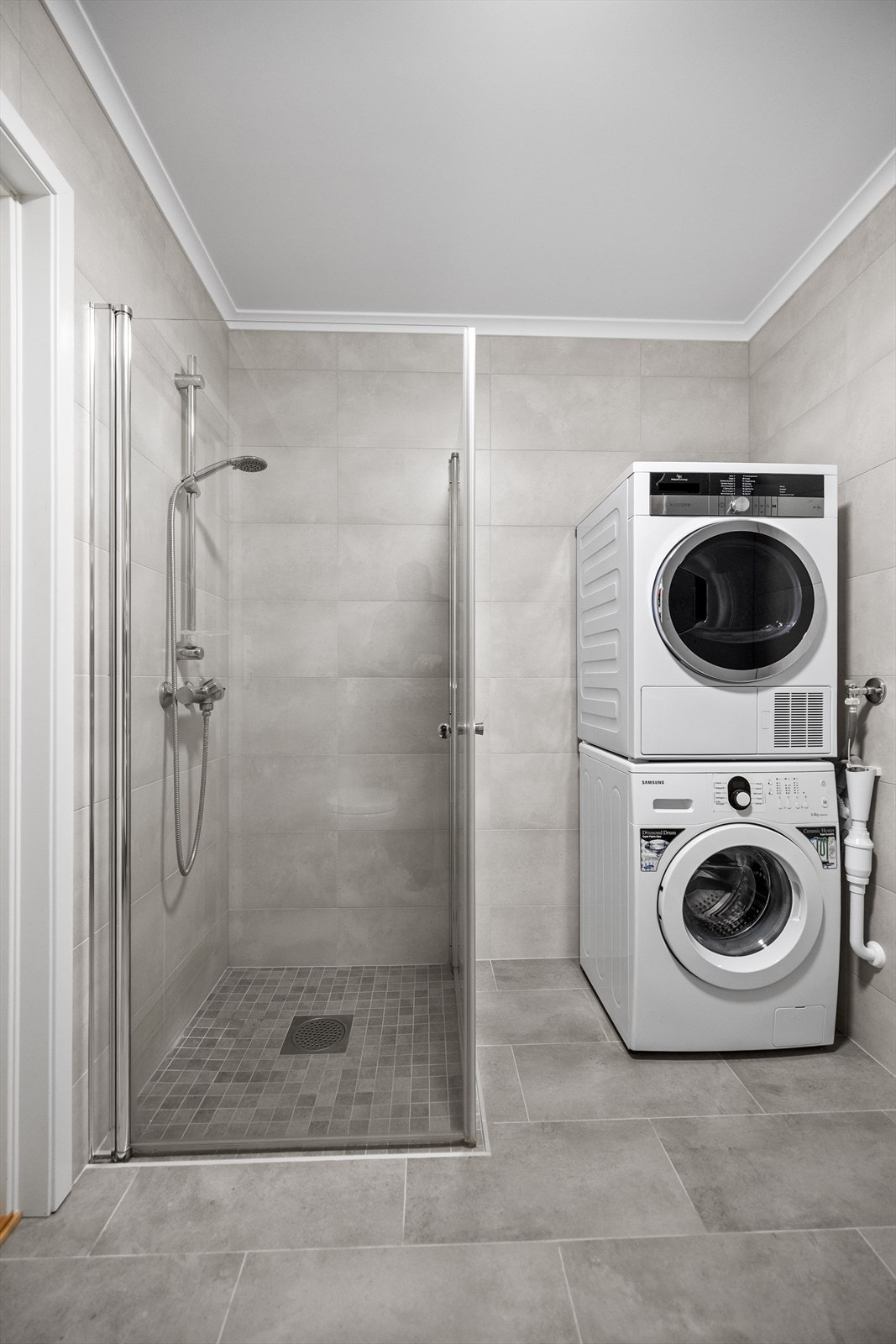 Dusjnisje med glassdører og opplegg for vaskemaskin gir praktisk bruk. Galleribilde