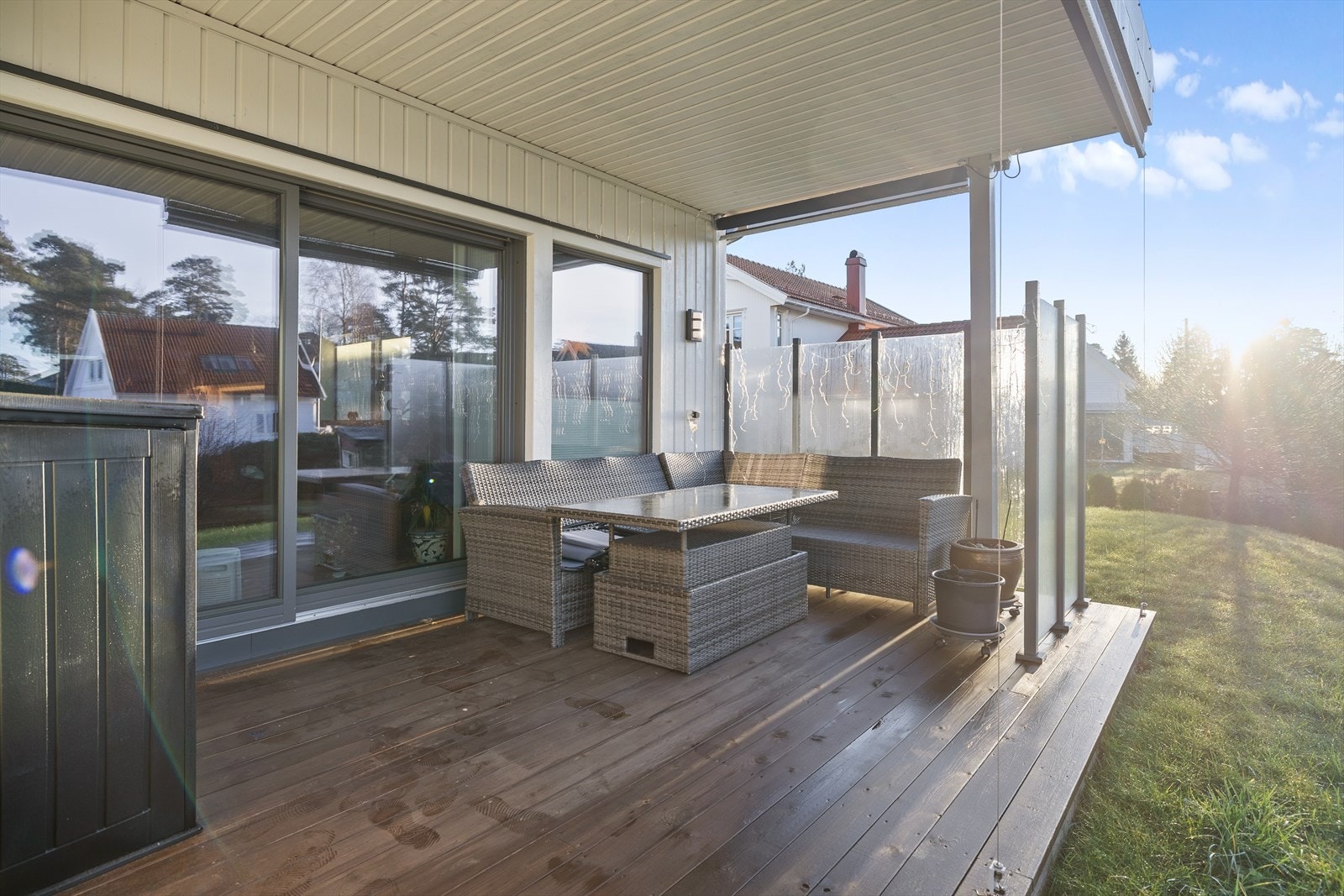Beiset terrassegulv gir en solid og innbydende uteplass med glasslevegg. Galleribilde