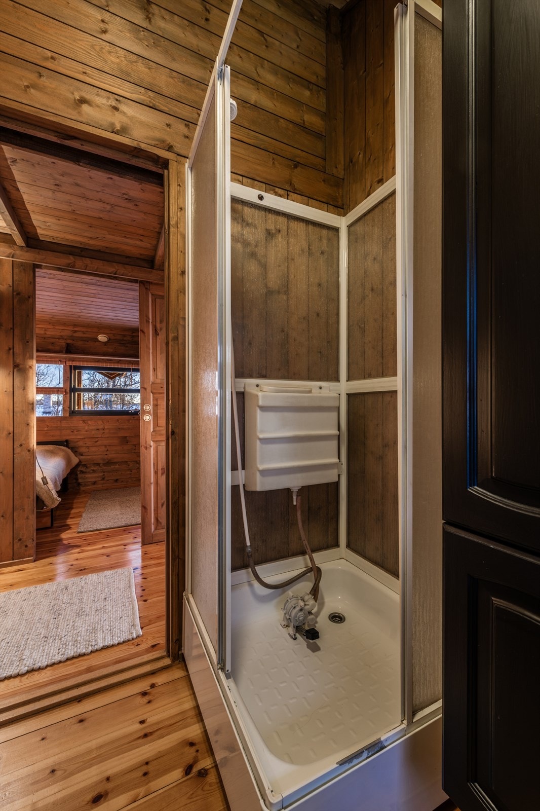 Badet er innredet med servantinnredning og dusjkabinett med vannbeholder og fotpumpe. Galleribilde