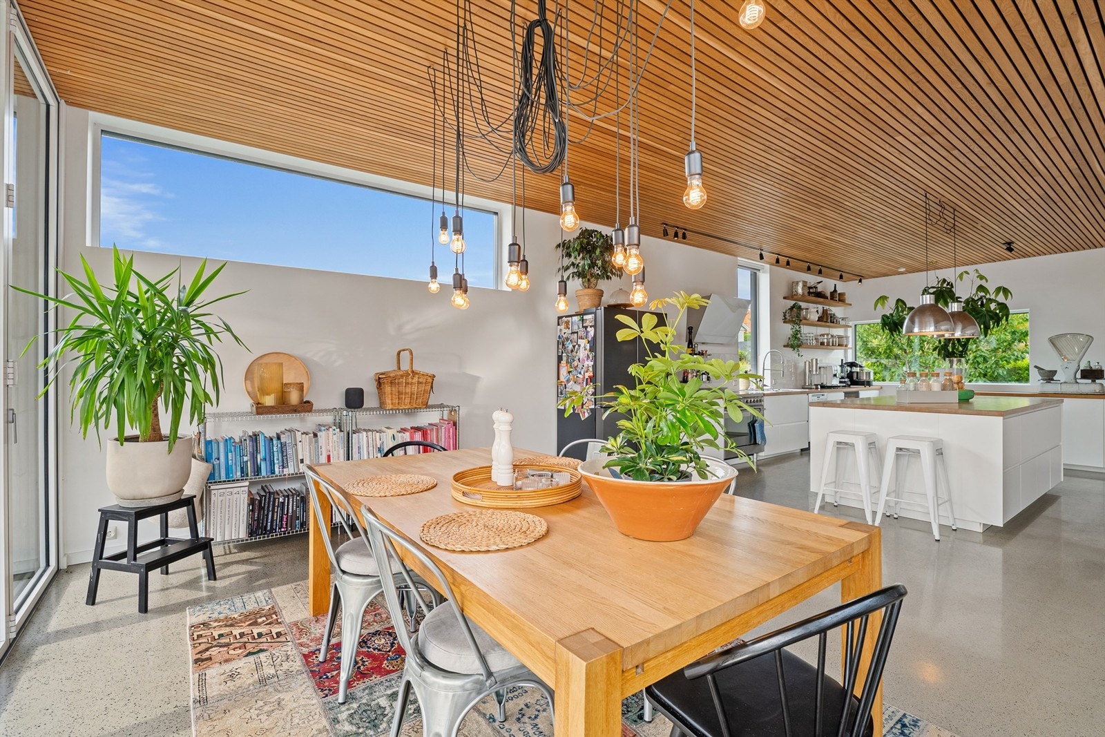 God takhøyde og store vindusflater som slipper inn den blå himmelen og grønt arealene som står fint til naturmaterialene inne på kjøkkenet Galleribilde