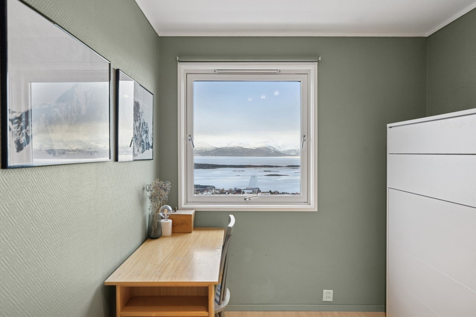 Stort vindu gir godt med naturlig lys og skaper en trivelig atmosfære, samtidig som rommet har fleksible møbleringsmuligheter for ulike behov. Galleribilde