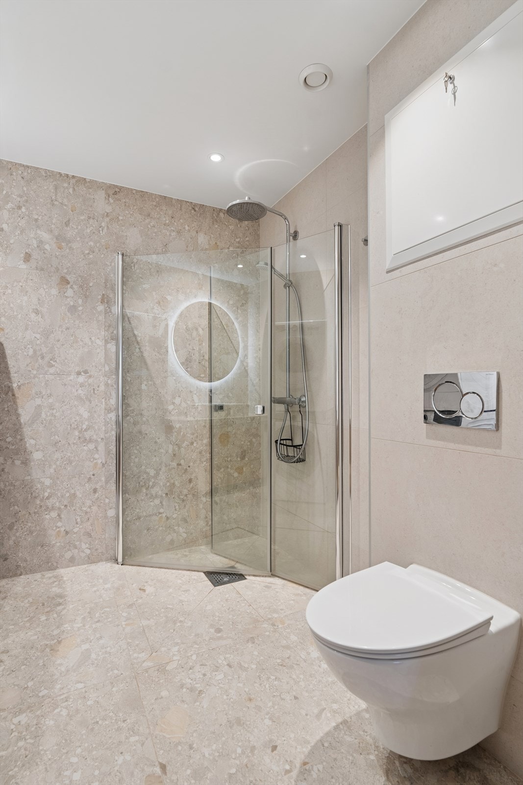 Innredningen består av servant med speil og integrert belysning, vegghengt toalett og dusjhjørne med glassdører. Badet har opplegg for vaskemaskin og mekanisk ventilasjon via sentralavtrekk. Galleribilde