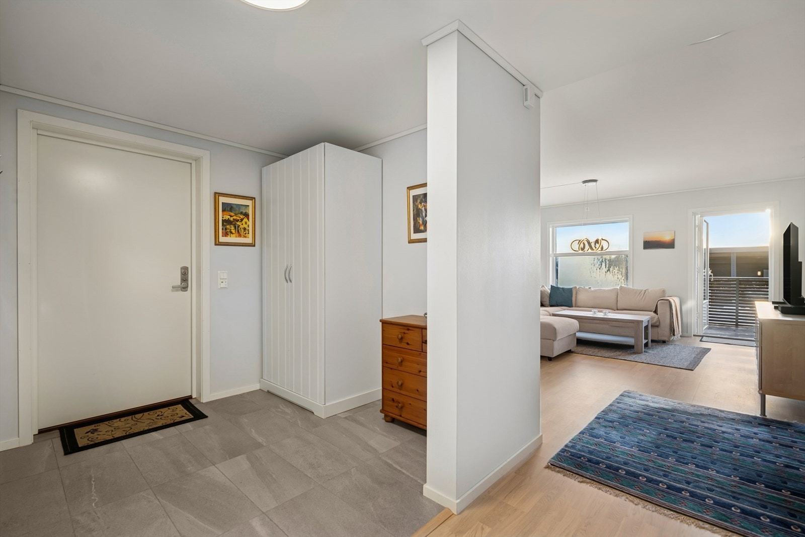 Du ønskes velkommen inn i en lys og flislagt entré med varmekabler i gulvet - en detalj som gir ekstra komfort i hverdagen. Her finner du et praktisk garderobeskap med god plass til oppheng av yttertøy og sko. Galleribilde