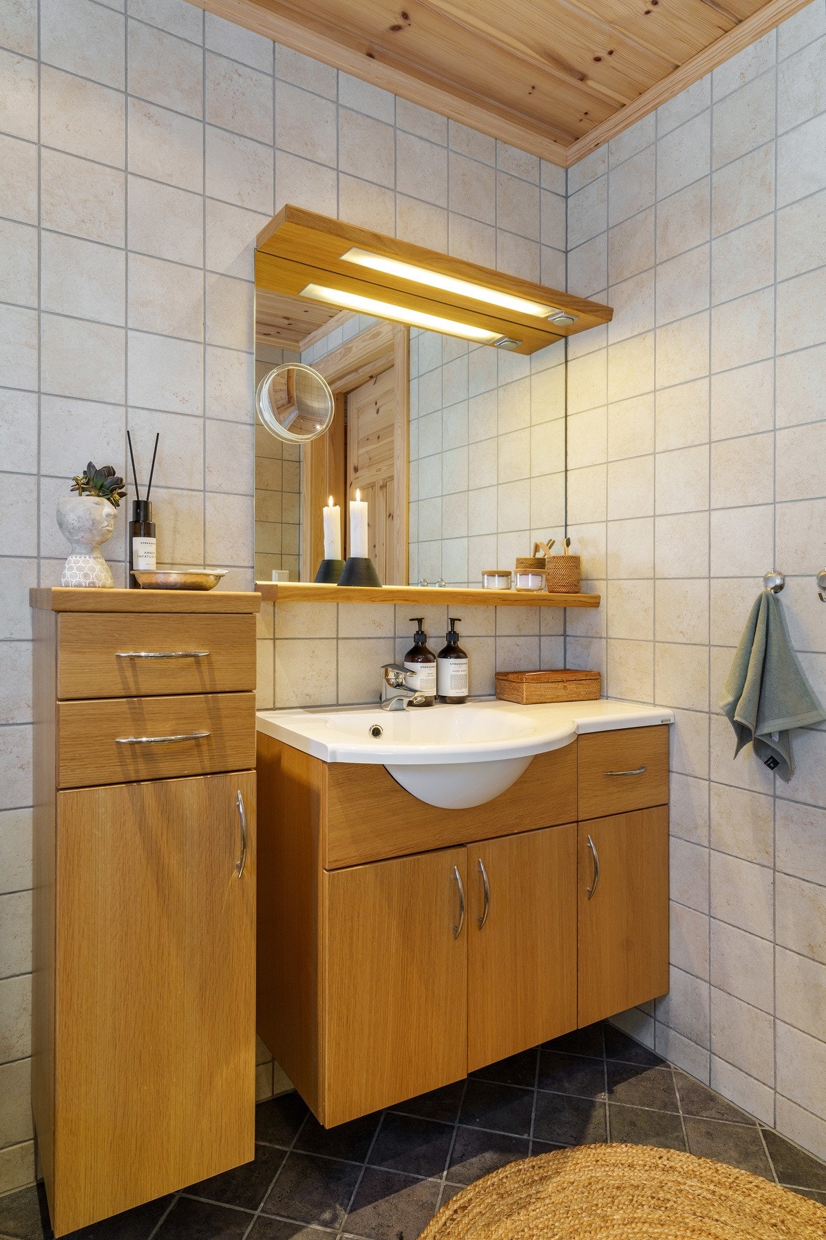 Baderomsinnredning med helstøpt servantplate, klosett og glassvegger i dusjhjørnet med skyvedør, det er også installert elektrisk styrt vifte i vegg. Galleribilde