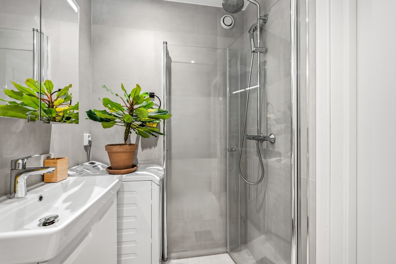 Dusjhjørne med svingdører og regnfallsdusj gir en praktisk og funksjonell baderomsløsning, med naturlig avtrekksventilasjon via vegg Galleribilde