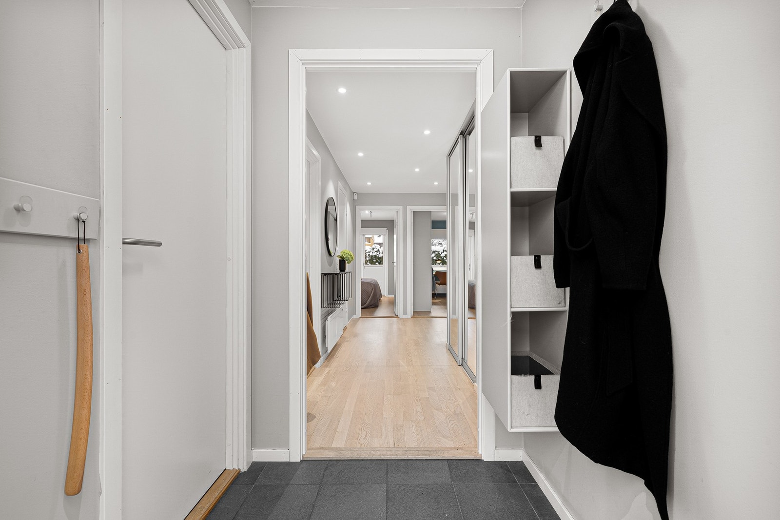 Innbydende, flislagt entré og gang med oppbevaring i skyvedørsgarderobe. Galleribilde