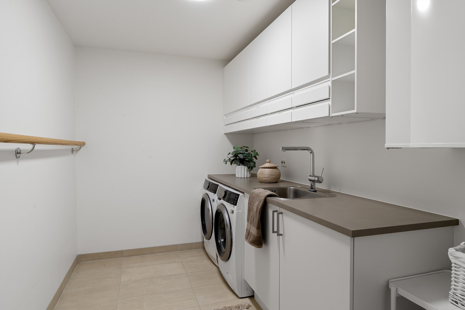 Praktisk separat vaskerom med fliser på gulv, god skapplass og utslagsvask. Galleribilde