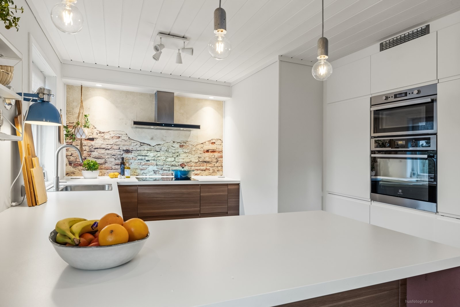 Pent kjøkken med glatte kjøkkenfronter. Montert kjøkkenventilator over koketopp. Galleribilde