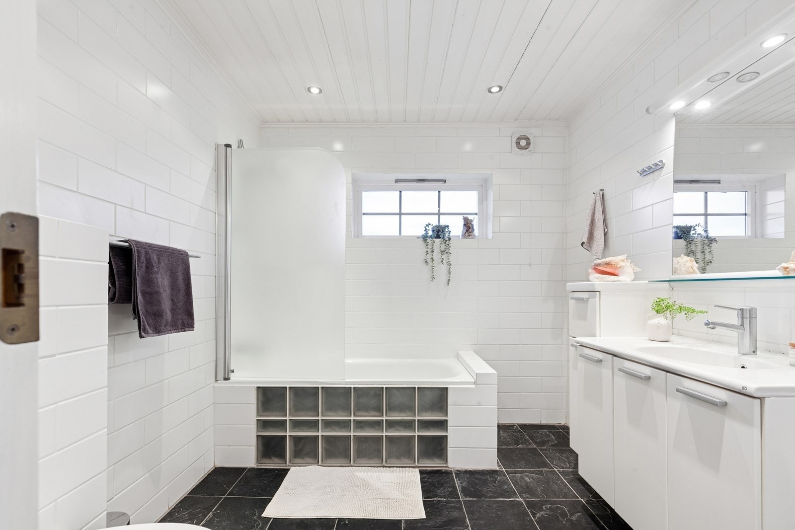 Pent, flislagt bad fra 2006. Badet er innredet med innmuret badekar med dusjvegger, vegghengt toalett og vask. Varmekabler i gulv og spotter i tak. Galleribilde