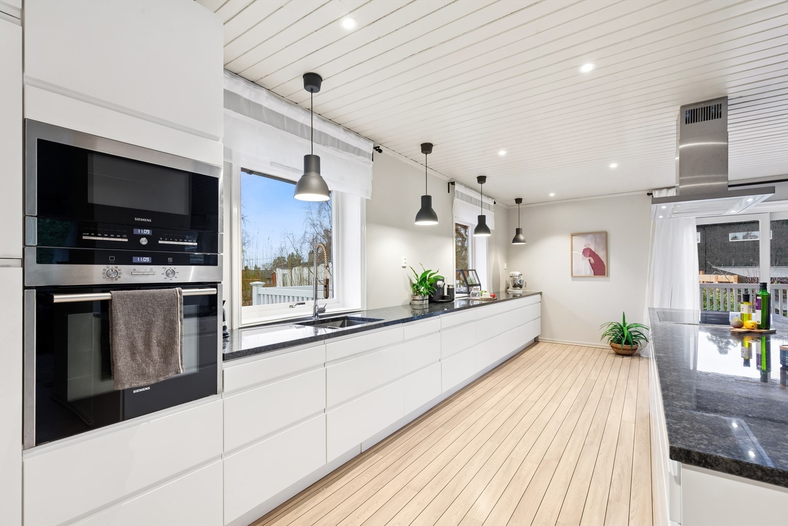 Kjøkken med hvite, slette fronter og benkeplate av stein med høy kvalitet. Galleribilde