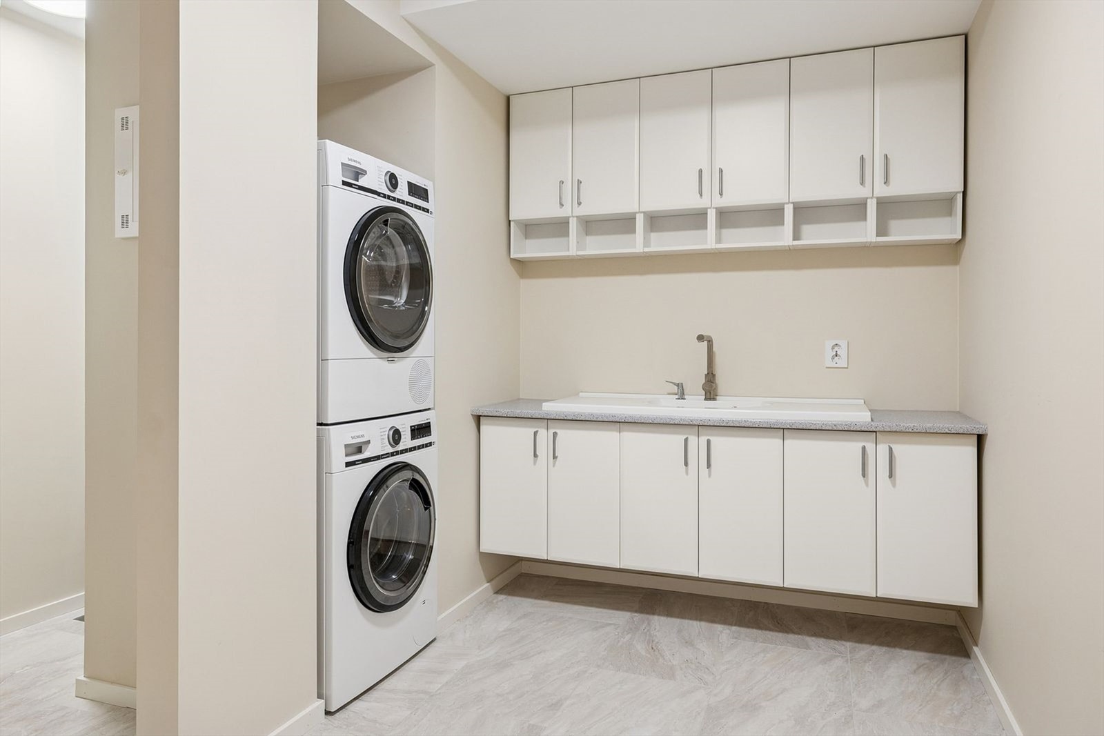 I kjelleretasjen er det et praktisk, moderne vaskerom med flislagt gulv og gulvvarme Galleribilde