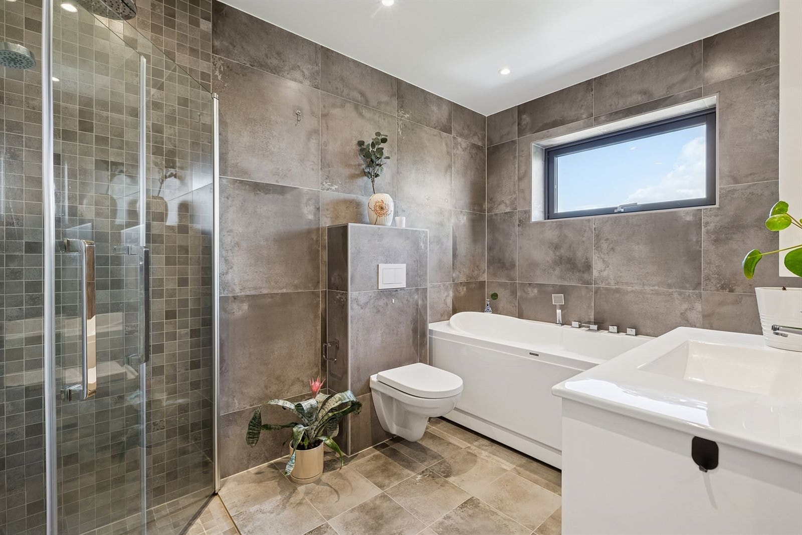 Romslig, flislagt bad med gulvvarme og downlights i himling Galleribilde