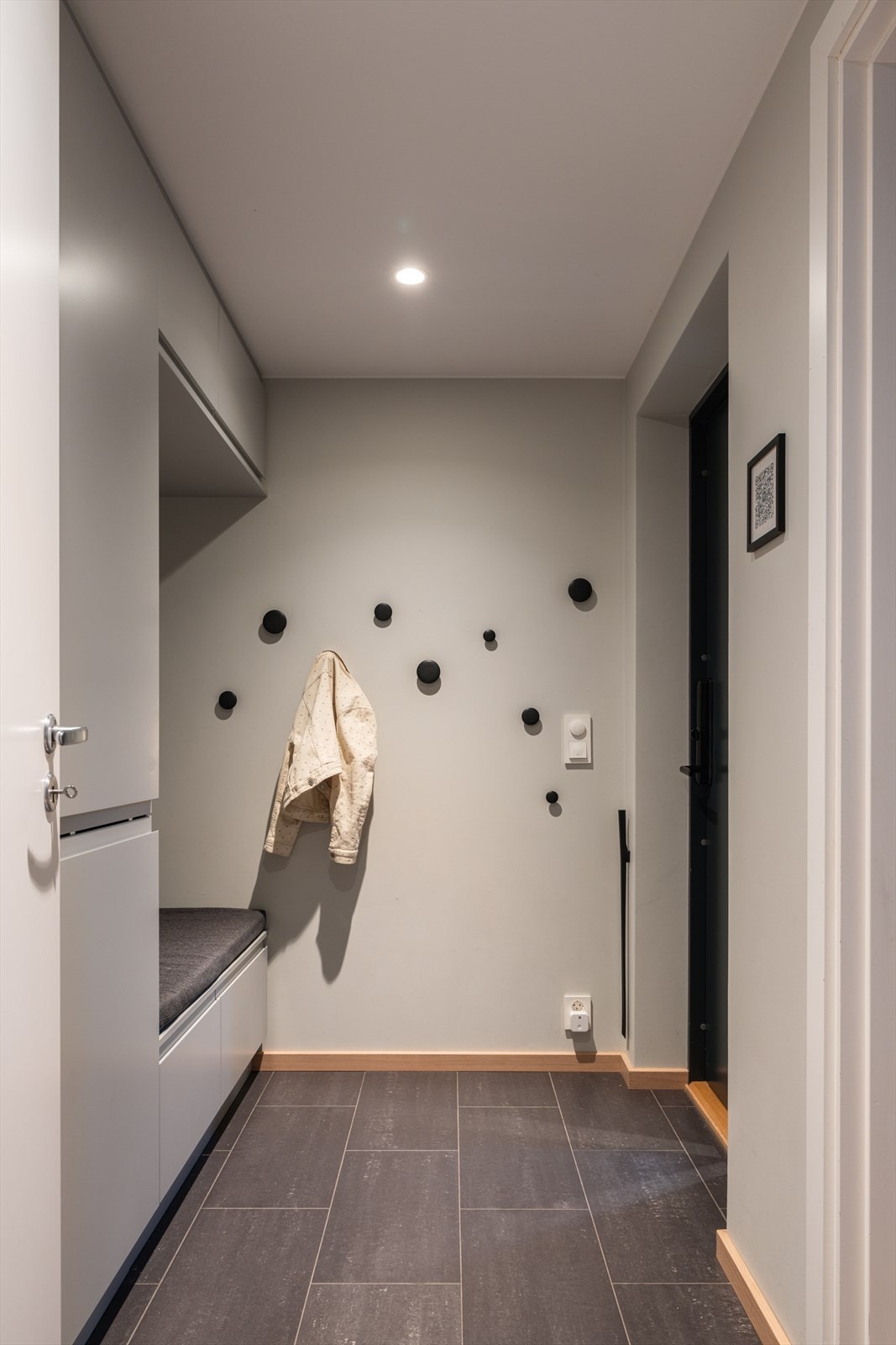 Romslig og innbydende entré med plassbygget garderobeløsning som gir rikelig med oppbevaringsplass. Praktisk sittebenk gjør hverdagen enkel, og rommet er flislagt med slitesterkt gulv. Det er varme i gulvet. Galleribilde